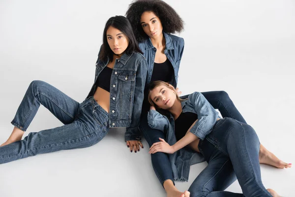 Aus der Vogelperspektive: junge interrassische Frauen im Jeans-Outfit posieren auf Weiß — Stockfoto