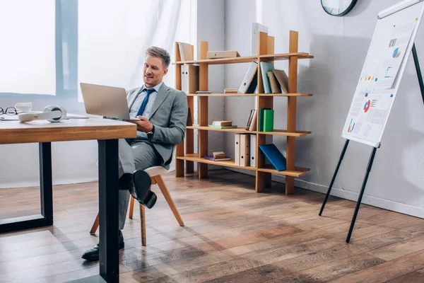 Uomo d'affari sorridente che utilizza il computer portatile mentre lavora in ufficio — Foto stock