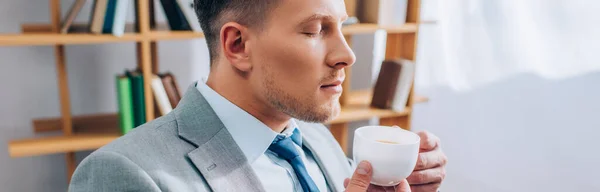 Businessman with closed eyes holding cup of coffee in office, banner — Stock Photo