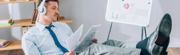 Young businessman in headphones doing paperwork in office, banner — Stock Photo