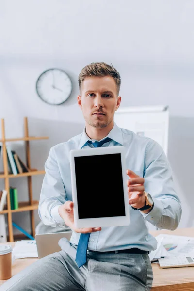 Uomo d'affari che mostra tablet digitale vicino al caffè per andare e carte sul tavolo di lavoro — Foto stock
