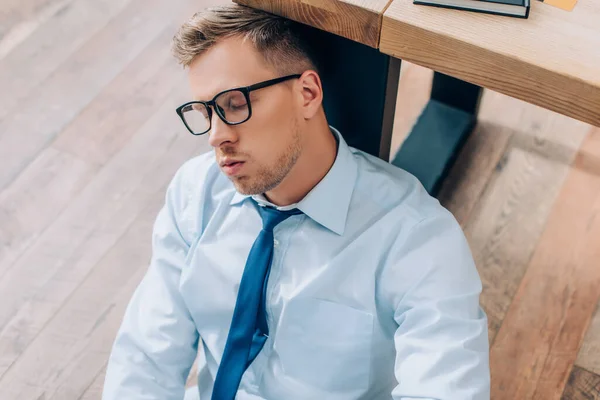Empresário em óculos dormindo perto da mesa no escritório — Fotografia de Stock