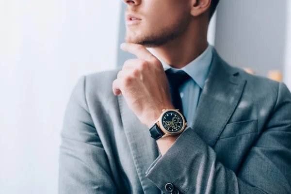 Обрізаний вид наручного годинника на руці молодого бізнесмена на розмитому фоні — стокове фото