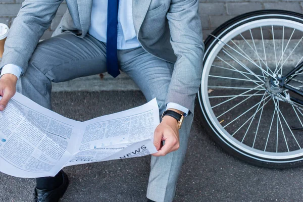 Vista cortada de empresário lendo jornal perto de bicicleta na passarela — Fotografia de Stock