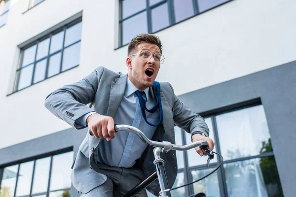 Захоплений бізнесмен їздить на велосипеді біля будівлі на відкритому повітрі — стокове фото