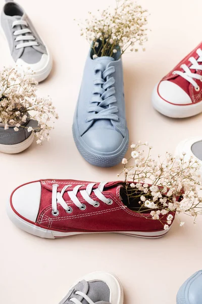 Lässige Turnschuhe und Wildblumen auf weißem Hintergrund — Stockfoto