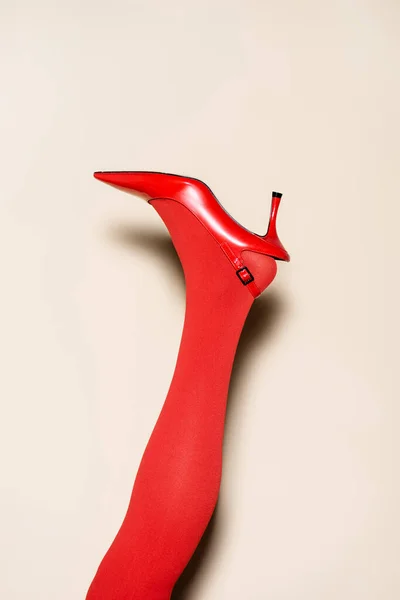 Обрізаний вид на жіночі ноги в червоних колготках і взуття на бежевому фоні — стокове фото