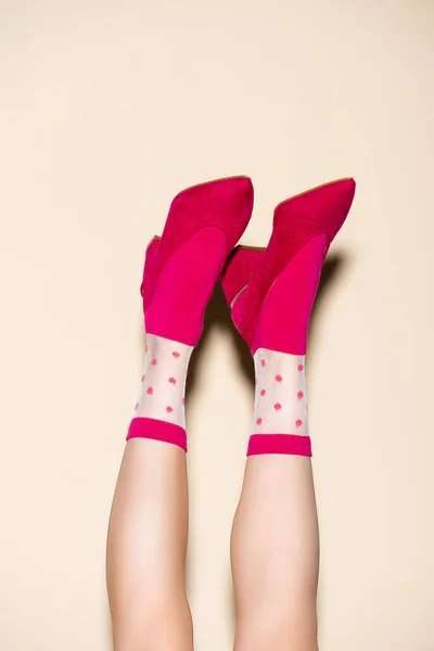 Cropped view of female legs in pink retro socks and shoes on beige background — Stock Photo