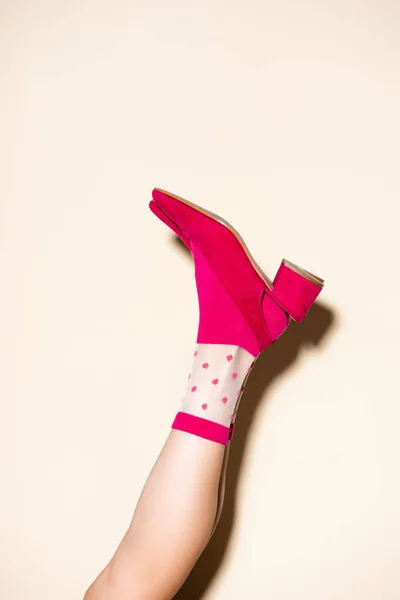 Vista recortada de la pierna femenina en calcetines retro rosados y zapatos sobre fondo beige - foto de stock
