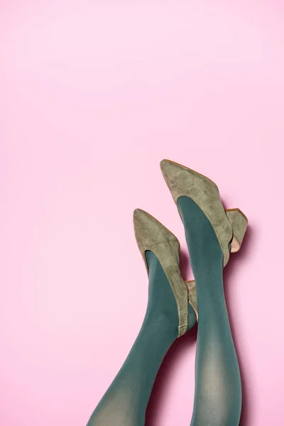 Abgeschnittene Ansicht weiblicher Beine in grünen Strumpfhosen und Retro-Schuhen auf fliederfarbenem Hintergrund — Stockfoto