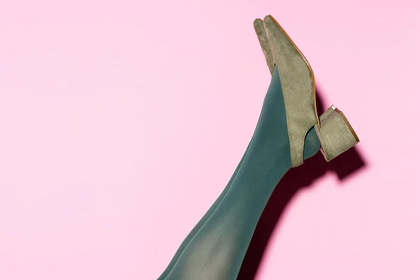 Cropped view of female leg in green tights and retro shoes on lilac background — Stock Photo