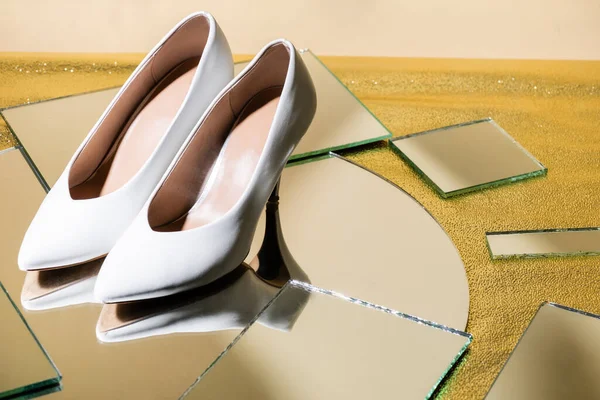 Elegant white heeled shoes on mirror surface — Stock Photo