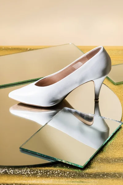 Elegant white heeled shoe on mirror surface — Stock Photo
