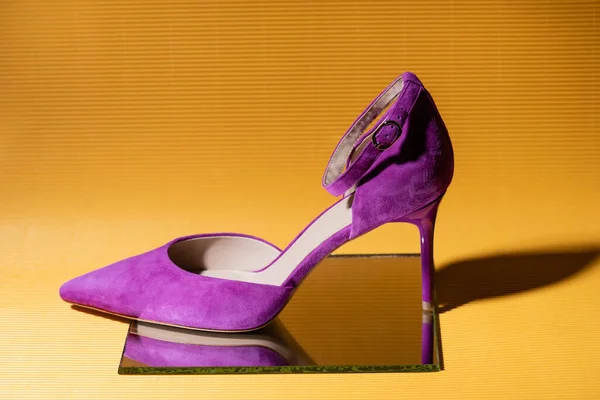 Elegant violet suede heeled shoe on mirror on yellow background — Stock Photo