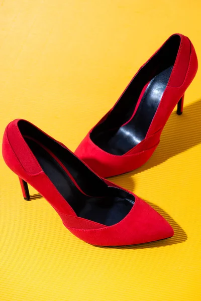 Elegant red suede heeled shoes on yellow background — Stock Photo