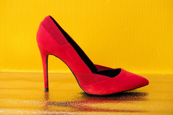 Elegante scarpa con tacco in camoscio rosso su sfondo giallo — Foto stock