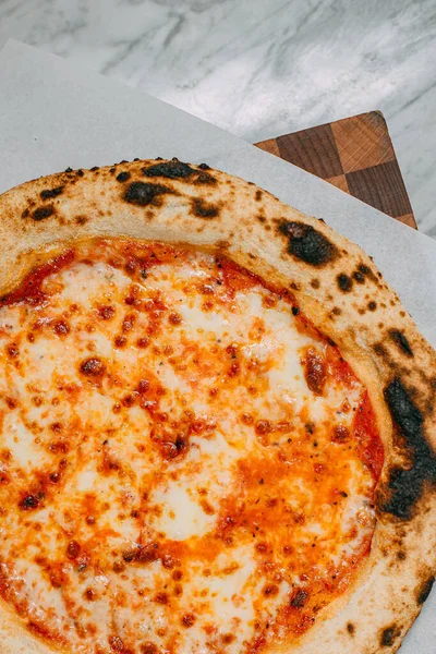 意大利热披萨放在大理石桌上 图库照片