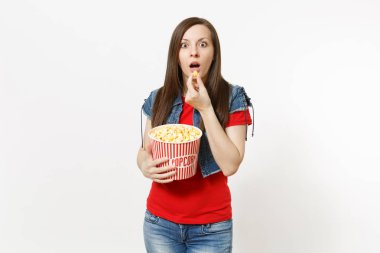 Holding ve beyaz arka plan üzerinde izole Kova patlamış mısır yemek genç şok güzel esmer kadını rahat kıyafetler film filmi izlerken portresi. Sinema kavramı duygular