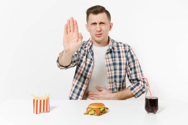 Hastalık adam ellerini karın bölgesinde ağrı, masada hamburger, patates kızartması, cola beyaz arka plan üzerinde izole cam ile karın ağrısı. Doğru beslenme veya Amerikan Klasik fast food alanı kopya alanı