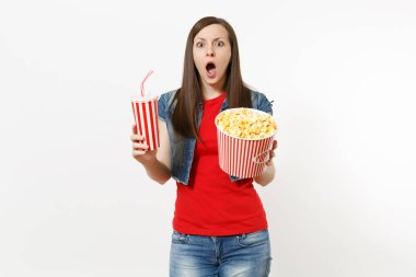 Film film izlerken, kova patlamış mısır ve kola veya kola beyaz arka plan üzerinde izole plastik bardak tutan rahat kıyafetler şok endişe kadında genç portresi. Sinema kavramı duygular