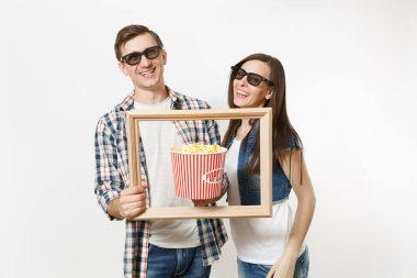 Genç çift, kadın ve erkekte 3d gözlük ve rahat kıyafetler tarihte film film izlerken gülümsüyor, kova patlamış mısır ve resim çerçevesinin holding beyaz arka plan üzerinde izole. Sinema kavramı duygular