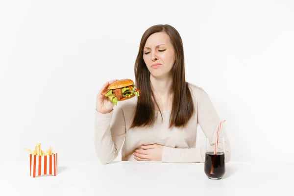 病気女痛み腹部に手を置く ハンバーガー フライド ポテト 白い背景で隔離のガラス瓶の中のコーラとテーブルで胃痛 適切な栄養やアメリカの古典的なファーストフード コピー スペース — ストック写真