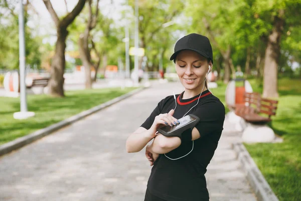 Siyah müzik dinleme, cep telefonu uygulaması çalıştıran veya jogging, Şehir Parkı mekanlarda eğitim için app kullanarak seyir kulaklıklar ile üniforma giyen genç atletik kız. Fitness, sağlıklı yaşam tarzı