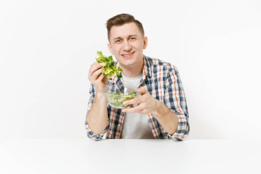 Beyaz arka plan üzerinde izole cam kase içinde yeşil taze salata ile masada oturan genç adam. Doğru beslenme, Vejetaryen Gıda, sağlıklı yaşam, diyet kavramı. Alan kopya alanı ile reklam