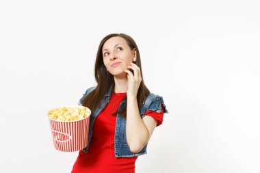 Film film izlerken, kova patlamış mısır holding, ararken, el Beyaz arka plan üzerinde izole çene yakın tutarak rahat kıyafetler genç dalgın güzel kadın portresi. Sinema kavramı duygular