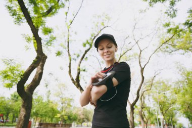 Siyah müzik dinleme, cep telefonu uygulaması çalıştıran veya jogging, Şehir Parkı mekanlarda eğitim için app kullanarak seyir kulaklıklar ile üniforma giyen genç atletik kız. Fitness, sağlıklı yaşam tarzı