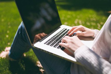 Başarılı kadın el üstünde klavye kırpılmış kapatın. Kadın dizüstü pc bilgisayar Park açık havada doğa üzerinde yeşil çim üzerinde çalışma çimen yere otur. Mobil ofis. Serbest iş kavramı