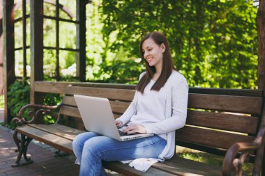 Genç başarılı işkadını hafif rahat kıyafetler içinde. Modern dizüstü pc bilgisayar Şehir Park açık havada doğa üzerinde çalıştığı bankta oturan kadın. Mobil ofis. Serbest iş kavramı