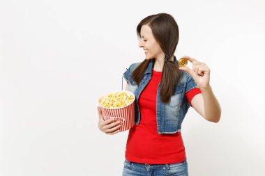 Film film izlerken, kova patlamış mısır ve beyaz arka plan üzerinde izole bitcoin tutarak rahat kıyafetler içinde kapalı gözlerle genç gülümseyen güzel esmer kadın portresi. Sinema kavramı duygular