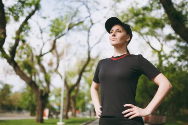 Siyah üniforma ve ayakta, dinlenme ve bir kenara Şehir Park açık havada çalışan, eğitimden sonra seyir kap içindeki genç atletik güzel esmer kız portresi. Fitness, sağlıklı yaşam konsepti
