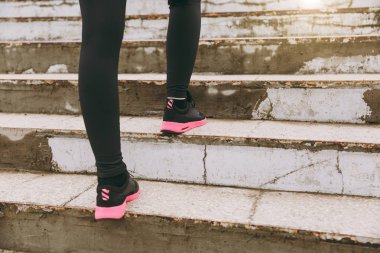 Kırpılan fotoğrafı yakın çekim Kadın bacak spor giyim, siyah ve pembe kadın spor ayakkabı spor egzersizleri, açık havada merdiven çıkma yapıyor. Fitness, sağlıklı yaşam konsepti. Kopya alanı reklam için