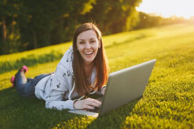 Genç öğrenci rahat kıyafetler içinde kadın akıllı. Çim, dizüstü pc bilgisayar Şehir Park açık havada Güneş çim yeşil çim üzerinde üzerinde çalışıyor yatan kadın. Mobil ofis. Serbest iş kavramı