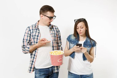 Genç çift, kadın ve erkekte 3d gözlük, rahat kıyafetler kova patlamış mısır cep telefonuyla beyaz arka plan üzerinde izole tutan tarihi film film izlerken rahatsız. Sinema kavramı duygular