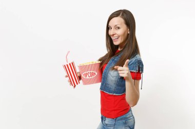 Film film izlerken, kova patlamış mısır ve kola veya kola işaret parmağı plastik bardak beyaz arka plan üzerinde izole kamera tutan genç gülümseyen güzel kadın portresi. Sinema duygular