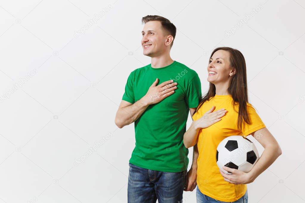 Emotional couple, woman man, football fans in yellow green t-shirt cheer up support team with soccer ball singing national country anthem isolated on white background. Sport leisure lifestyle concept