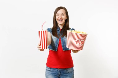 Film film izlerken, kova patlamış mısır ve kola veya kola plastik bardak beyaz arka plan üzerinde izole kamera üzerinde gösterilen rahat kıyafetler içinde genç gülümseyen çekici kadın portresi. Sinema duygular