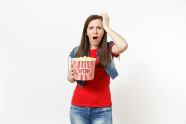 Genç portresi tahriş olmuş film film izlerken, kova patlamış mısır holding, el yakınındaki beyaz arka plan üzerinde izole kafa tutarak rahat kıyafetler şok esmer kadın. Sinema kavramı duygular