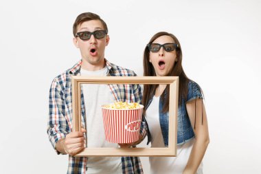 Genç şok çift, kadını ve kova patlamış mısır ve resim çerçevesinin tutan adam 3d gözlük ve rahat kıyafetler tarihte, film film izlerken beyaz arka plan üzerinde izole. Sinema kavramı duygular