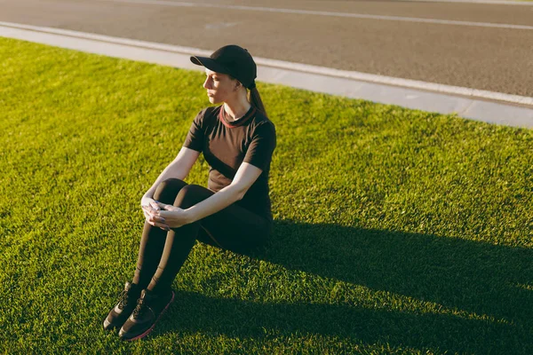 Молодая Спортсменка Черной Форме Шапочка Отдыхает Зеленой Лужайке Парке Поля — стоковое фото