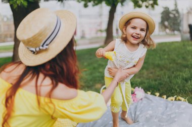 Sarı giysili kadın park kalan çim üzerinde oynamak ve eğlenmek küçük şirin çocuk bebek kız ile sabun köpüğü üfleyici tutun. Anne, küçük çocuk kızı. Anneler günü, aşk aile, ebeveynlik, çocukluk