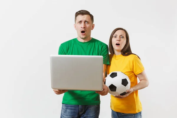Shocked couple woman man, football fans in yellow green t-shirt cheer up support team with soccer ball, watching game on pc laptop isolated on white background. Sport family leisure lifestyle concept