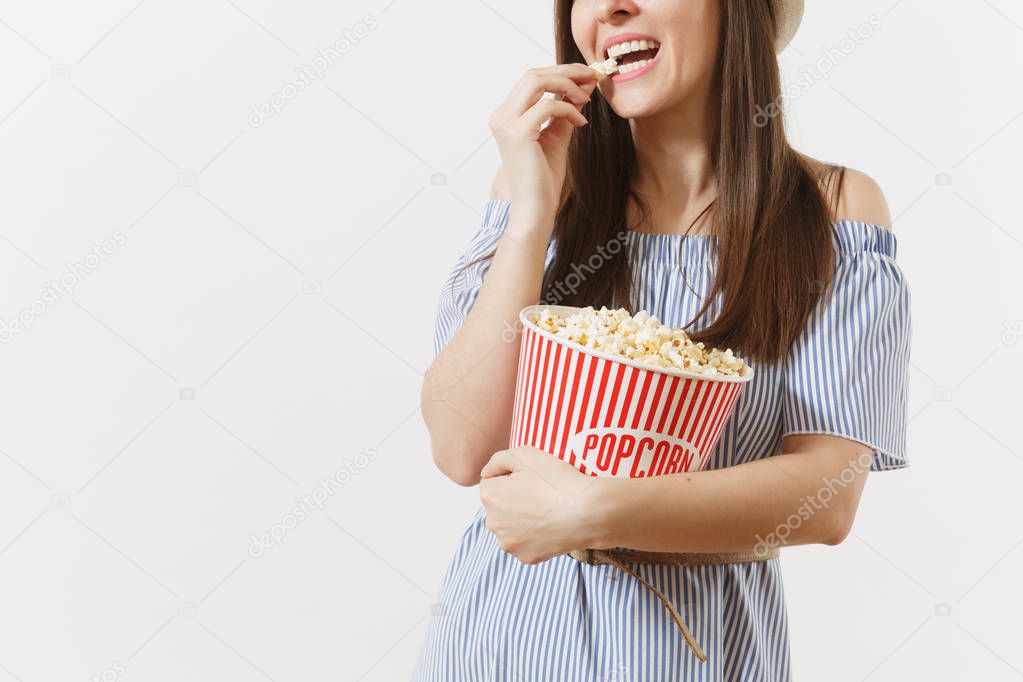 Cropped photo woman in blue dress, hat watching movie film eating popcorn from bucket isolated on white background. People, sincere emotions in cinema, lifestyle concept. Advertising area. Copy space