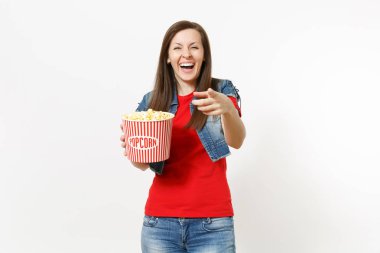 Film film izlerken, kova patlamış mısır holding ve beyaz arka plan üzerinde izole kamera işaret parmağını göstererek rahat kıyafetler genç gülmek güzel kadın portresi. Sinema kavramı duygular