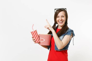 Kova patlamış mısır, plastik bardak kola veya kola işaret parmağı bir kenara boşaltmak üzerinde tutan genç gülümseyen kadın 3d gözlük film filmi izlerken beyaz arka plan üzerinde izole. Sinema duygular