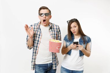 Genç çift, kadın ve beyaz arka plan üzerinde izole cep telefonu kullanan adam 3d gözlük ve rahat kıyafetler Kova patlamış mısır, holding tarihte film film izlerken şok. Sinema kavramı duygular