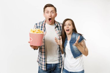 Genç çift, kadın ve erkekte tarihte film film izlerken, kova patlamış mısır holding, çığlık ve beyaz arka plan üzerinde izole eller yayılan rahat kıyafetler şok. Sinema kavramı duygular
